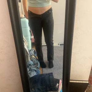 Svarta lågmidjade jeans straight fit - Säljer ett par svarta jeans med låg midja och klassisk rak passform. Jeansen har fem fickor, bälteshällor och stängs med dragkedja och knapp. Perfekta för dig som gillar en enkel och clean look.