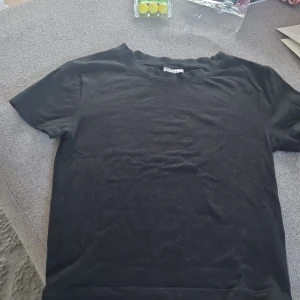 Svart t-shirt från H&M Divided, S - En enkel svart t-shirt från H&M Divided i storlek S. Modellen har rund hals och korta ärmar, perfekt för en clean och stilren look. Materialet är mjukt och skönt bomullstyg som sitter bekvämt mot kroppen. Passar dig som gillar basic och minimalistisk stil.