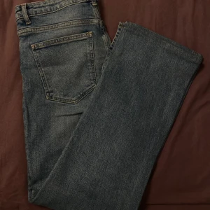Blå raka jeans i klassisk modell - Snygga blå jeans med rak passform och slits längst nere vid foten. Jeansen är i nytt skick och aldrig använda. 