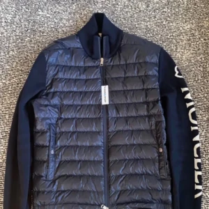 Moncler jacka - Snygg mörkblå pufferjacka från Moncler med quiltad framsida och stickade ärmar. Jackan har dragkedja framtill och Moncler-logga i vitt längs ena ärmen. Jackan är från kicks N stuff och köpt för 7000.       Kom privat för fler frågor. (Äkta såklart) med fungerande tagg osv.