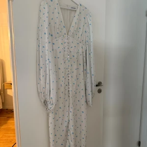 Adoore- Positano dress - Supersöt långklänning från Adoore i vit med små blå blommor. Klänningen har v-ringning, långa puffärmar och knappar hela vägen framtill. Materialet är glansigt och känns lyxigt, perfekt för dig som gillar romantiska detaljer och blommigt. Hör av dig vid intresse 🌸🌟🙌🏼