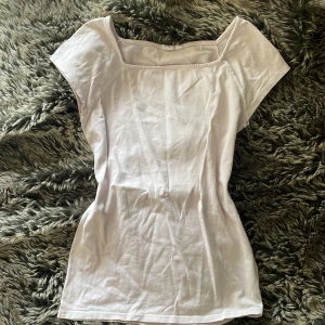 Ljusrosa topp med fyrkantig hals från GAP - Säljer en ljusrosa topp från GAP med snygg fyrkantig halsringning och korta ärmar. Toppen är figurnära och tillverkad i mjuk bomull, perfekt för en chill och stilren look. Enkel design utan mönster eller detaljer, passar till allt.