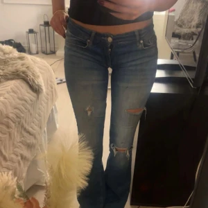 Blå bootcut jeans med slitningar - Låg Midjade Snygga blå jeans med bootcut-modell och slitna detaljer på. Säljer pga kommer inte till användning skriv för mått osv eller fler bilder.