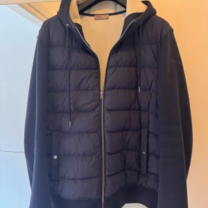 Mörkblå pufferjacka med huva från Herno - Jackan är köpt på NK herr för 9000kr och är en riktigt bra höst/vår jacka.. Snygg mörkblå pufferjacka från Herno med quiltad front, huva med dragsko och hel dragkedja. Jackan har mjuka ärmar och baksida i bomullsmix, vilket ger en sportig och avslappnad vibe. Perfekt för kyliga dagar när du vill vara både varm och stilren.  Passar dig som har M eller L eller lite längre. Köpt vintern 2024 och använd varsamt