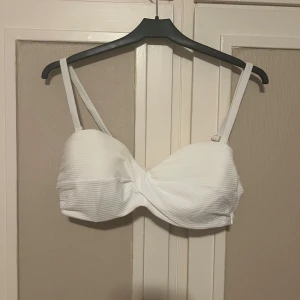Vit bikini-bh  - Supersnygg bikini-bh från H&M i storlek 85C. Den är vit med ribbad struktur och har justerbara axelband med guldfärgade detaljer. Använd 1-2 gånger men passade inte mig. Perfekt för stranden eller poolen i sommar!