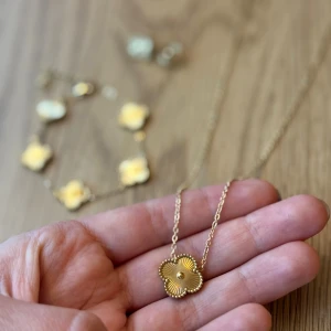 Guldfärgat klöver smyckeset - Snyggt smyckeset med halsband, armband och örhängen i guldfärg. Gjort i rostfritt stål! Alla delar har klöver berlocker med räfflad yta och små pärldetaljer i mitten. Setet levereras i glittriga presentpåsar med stjärnor och månar. Van cleef inspirerat :) Inte använt av mig, så nytt i princip! 