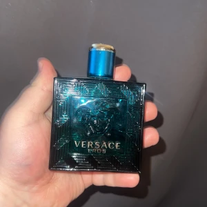 Versace Eros herrparfym - Versace Eros herrparfym i en stilren, fyrkantig flaska i turkost glas med Medusa-huvudet ingraverat på framsidan. Flaskan har ett blått lock med gulddetalj och rymmer en fräsch, maskulin doft.möngden kvar syns på andra bilden ungefär 40 ml kvar