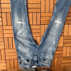 Replay  - Säljer ett par replay  jeans i klassisk blå tvätt med slitningar och lätt distressed look. Jeansen har fem fickor och smal passform. W31 L34. Skriv om du undrar något, pris kan diskuteras vid snabb affär 
