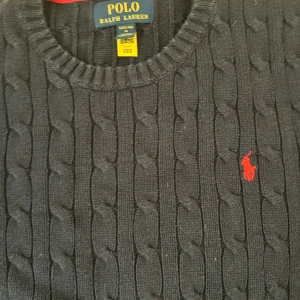 Mörkblå kabelstickad tröja Polo Ralph Lauren - Kabelstickad mörkblå tröja från Polo Ralph Lauren. Andvänd väldigt fåtal gånger, inga defekter. Strl 14-16.