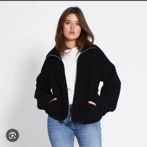 Svart teddyjacka med dragkedja - Mysig svart teddyjacka med dragkedja framtill och två stora fickor. Jackan har en avslappnad passform och hög krage, perfekt för kyliga dagar. Passar dig som gillar en enkel men trendig stil. Slutsåld på lager 157, jag har M i den för en lite större jacka som inte blir för tajt. Passar även S🤎🍂
