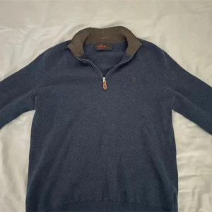 Mörkblå half zip-tröja Morris 100% merinoull xs/s - Snygg marinblå tröja från Morris i 100% merinoull. Tröjan är i storlek M men har krymt lite så passar xs/s. Tröjan har en halv dragkedja och kontrastfärgad krage i beige. Tröjan har lång ärm, ribbade muddar och en broderad logga på bröstet. Perfekt för lager-på-lager och chill stil. Den är i princip oanvänd och är alltså i mycket fint skick. MVH Hannes!