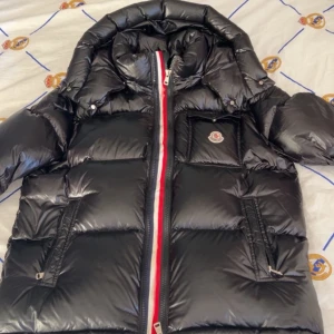 Svart Moncler jacka - Jackan har röd, vit och blå rand längs dragkedjan, två sidofickor med dragkedja och en bröstficka. Perfekt för kalla dagar och riktigt snygg streetstil. Pris kan diskuteras.
