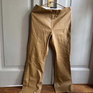 Beiga bootcut byxor I konstläder från Soaked Luxury - Beiga bootcut-byxor från Soaked Luxury i fint konstläder - storlek M. 