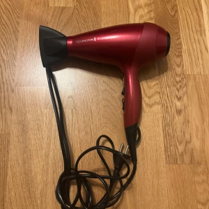 Remington Silk Hårfön - Remington Silk hårfön i rött, med stylingmunstycke och lång sladd. Flera värme- och hastighetsinställningar. Produkten ser ut att vara i gott skick utan synliga defekter eller slitage. Perfekt för snabb och effektiv hårtorkning.