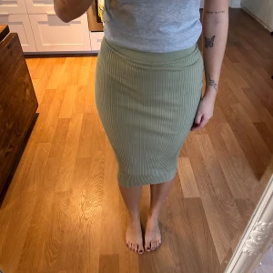 Ribbad grön midikjol - Snygg ribbad kjol i ljusgrön färg med tight passform och midilängd. Kjolen är stickad och har en elastisk midja som sitter bekvämt. .