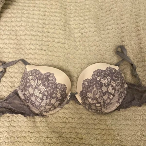 Lila spets bh Victoria's Secret - Säljer en snygg bh-n från Victoria's Secret i modellen Dream Angels. Toppen är beige med lila spetsdetaljer och har axelband. Spetsen har ett blommigt mönster som ger en lyxig vibe. Perfekt för dig som vill ha något extra fint under kläderna.