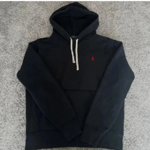 Ralph lauren hoodie  - ~Svart hoodie från Polo Ralph lauren med ett rött broderat Ralph lauren märke på bröstet~hoodien är i toppskick och har få tecken på användning~storleken är XS men skulle säga att den sitter mer som en S~nypris är 2200:- mitt pris är 999:-~hoodien har en qr kod som garanterar att den är äkta~är öppen för frågor och möjligtvis byten~Hör av er!