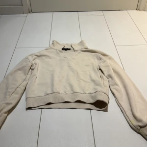 Beige croppad tröja från XOXO Friends - Säljer en beige croppad tröja från XOXO Friends med hög krage och långärmad design. Tröjan har ribbad nederkant och är tillverkad i mjuk bomull, perfekt för chill dagar. Enkel och stilren look som funkar till jeans eller mjukisbyxor.