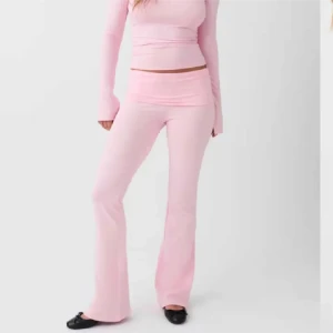 Ljusrosa bootcut mjukisbyxor - Säljer ett par ljusrosa mjukisbyxor med bootcut passform och låg midja. Byxorna är tillverkade i mjukt material som ger en skön känsla och har en enkel, stilren design utan synliga detaljer. Perfekta för en chill och trendig look.