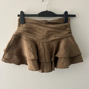 Khaki volangkjol från Zara - Säljer en khaki/olivgrön kortkjol från Zara med snygga volanger och draperad midja. Helt ny utan prislapp då jag köpte fel storlek.