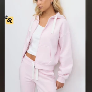 Ljusrosa hoodie med dragkedja - Säljer en ljusrosa hoodie med huva och vita snören. Tröjan har dragkedja framtill, två fickor och ribbade muddar vid ärmslut och nederkant. Tröjan är gråna fina Young och är i storlek s. Nästan inte använd.