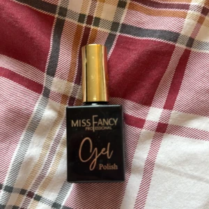 Miss Fancy Gel Polish svart/guld - Snygg gel polish från Miss Fancy Professional i en stilren svart flaska med guldig kork. Perfekt för dig som vill fixa naglarna hemma med salongskänsla. Flaskan är fyrkantig och känns lyxig med sin metalliska finish på korken. Färgen är stark rosa jätte fin dock är den på toppen där man ska se färgen borta annars inget fel alls finns kanske halva kvar skulle jag tippa på🤍