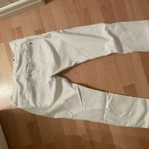 Vita jeansbyxor från dondup, stl 31 - Säljer ett par vita jeansbyxor från Dondup i storlek 31. Byxorna har klassisk femficksdesign, diskreta slitningar och raka ben. Materialet är bomull med en liten del elastan för extra stretch. Perfekta för dig som vill ha en clean och fräsch look.