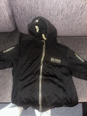 Hugo boss  - Hugo boss fleece, svart med guldiga detaljer, storlek M/L, har ett hål på vänster arm, men går lätt att sy ihop! Buda på!!
