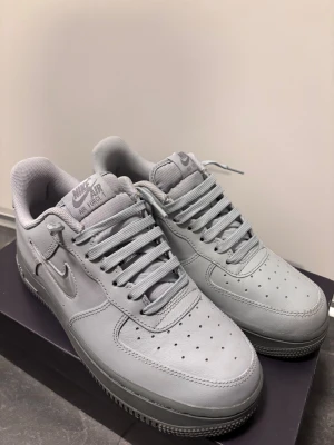 Nike Air Force 1 Jewel Wolf Grey - Nike Air Force 1 Jewel i färgen Wolf Grey/Cool Grey. Snygga sneakers med låg profil, platt sula och rund tå. Ovandel i grått skinn med matchande snörning och en glansig, liten Swoosh på sidan. Klassisk Air Force 1-design med robust gummisula. Använda Max 4 gånger! Låda följer med! Skriv vid minsta fundering!