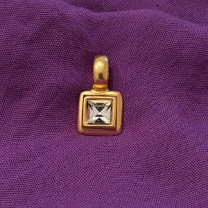 Guldigt hänge från Dyrberg Kern - Unikt fyrkantigt hänge från Dyrberg Kern i guldton med en klar, fyrkantig sten i mitten. Snygg och stilren design som passar perfekt till en kedja för att ge din look extra edge.