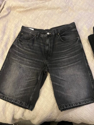 Svarta jeansshorts från Zara - Säljer ett par svarta jeansshorts från Zara med klassisk femficksdesign och raka ben. Shortsen har en snygg tvättad look och är tillverkade i bomull. Perfekta för en avslappnad stil under varmare dagar.