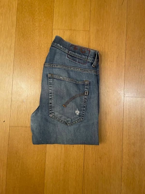 Dondup - Snygga Replay Anbass jeans i blå tvätt med slitningar och distressed detaljer. Modellen är skinny med normal passform och klassiska fem fickor. Jeansen har låg midja och är tillverkade i stretchigt denim för skön känsla. Perfekt för dig som gillar en cool och avslappnad stil.