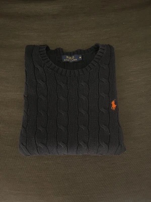 Mörkblå stickad tröja Polo Ralph Lauren - Kabelstickad mörkblå tröja från Polo Ralph Lauren i storlek M. Mycket fint skick