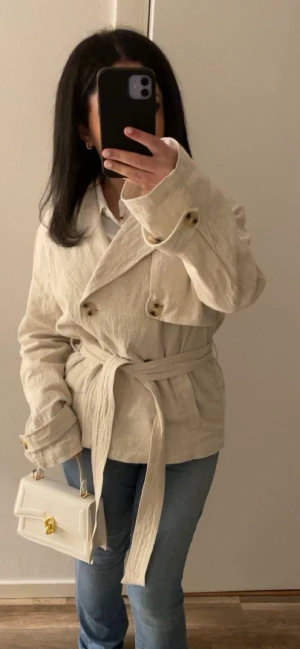Beige trenchcoat med bälte🤎✨ - Säljer en elegant och stilren kappa i en vacker neutral nyans. Perfekt för både vardag och fest! Kappan är gjord av ett lätt och luftigt material, vilket gör den bekväm att bära. Den har en smickrande siluett med bälte i midjan som framhäver figuren. Kappan är i mycket gott skick och redo att bli en favorit i din garderob! 😍👌🏽✨