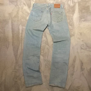 Levi's 501 ljusblå jeans W29 L32 - Ljusblå klassiska Levi's 501 jeans med rak passform och normal midja. Jeansen har fem fickor, knappgylf och den ikoniska läderpatchen bak i midjan. Tillverkade i slitstarkt bomullsdenim med snyggt tvättad look och subtila kontrastsömmar.
