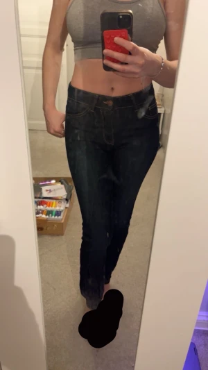 Mörkblå skinny jeans  - Snygga mörkblå jeans med skinny passform och medel hög midja. Klassisk femficksmodell med kontrastsömmar och knappstängning fram. Jeansen sitter tight längs benen och har en stilren look som funkar till många olika outfits.