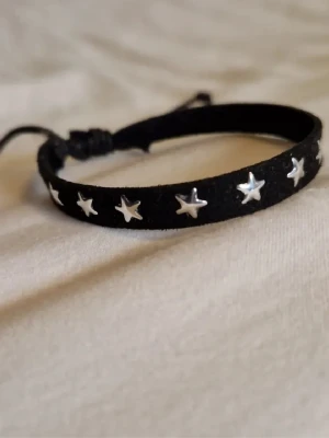 Svart armband med silver stjärnor - Ett svart armband med silverstjärnor. Perfekt till att poppa en outfit. Justerbar😊