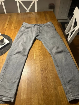 Grå jeans Tapered/Mike - Snygga grå jeans från Tapered/Mike med klassisk femficksdesign och raka ben som smalnar av mot ankeln. Jeansen har en cool tvättad look och är tillverkade i mjukt jeanstyg som sitter skönt hela dagen. Storleken är 29/30.