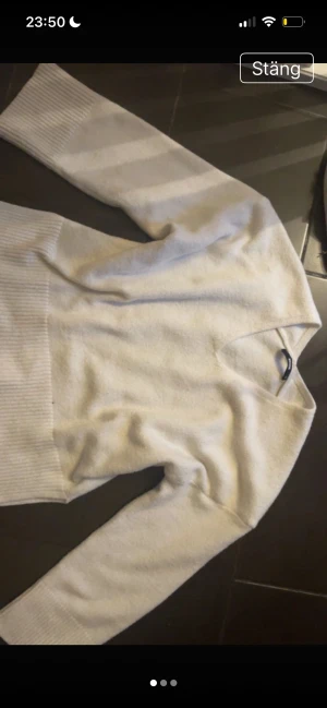 Vit stickad tröja med v-ringning Bikbok - Mysig vit stickad tröja från Bikbok i storlek XS. Tröjan har v-ringad hals, långa ärmar och breda ribbade muddar vid ärmslut och nederkant.