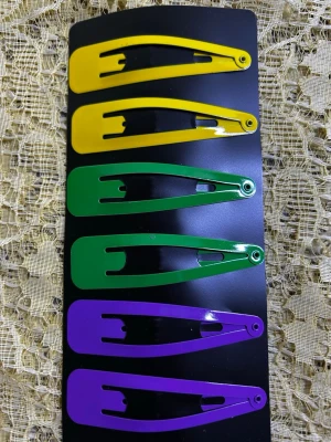 Färgglada Stora hårspännen  - Säljer ett set med sex hårspännen i metall, två gula, två gröna och två lila. Spännena har en klassisk, avlång form och är perfekta för att ge din frisyr en färgklick. Kommer på ett svart kort, redo att användas till din look.  29/ par 