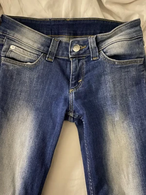 Cheap Monday blå jeans, storlek 27/30 - Snygga blå jeans från Cheap Monday med coolt slitna detaljer och klassisk logga med döskalle bak. Modellen har fem fickor, gul kontrastsöm och är tillverkad i stretchigt material för skön passform. Perfekt för dig som gillar streetstil. Den är i jätte bra skick och bootcut, stl 27/30