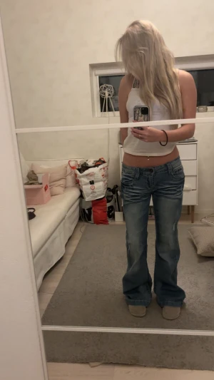 Blå bootcut jeans med slitningar - Säljer ett par vintage blå bootcut jeans med låg midja och snygga slitningar framtill. Jeansen har klassiska fem fickor och coola detaljer på bakfickorna.  Skulle säg att jeansen passar allt från xs-m beroende på hur man vill att dem ska sitta! För referens är jag en storlek xs/s!💘