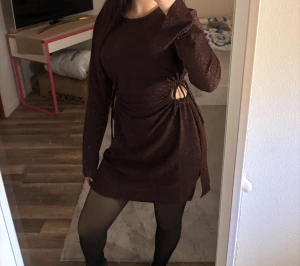 Brun glittrig kortklänning med snörning - Säljer en brun glittrig kortklänning från Bershka med långa ärmar och coola snörningsdetaljer i sidorna som ger en öppen look vid midjan. Endast använd 1 gång, ord pris 399kr🥰🤍