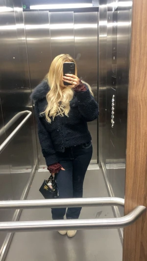 Mörkblå jacka med fluff - Säljer en mörkblå teddyjacka med fluffig krage och knappar framtill. Jackan har en croppad passform och är perfekt för dig som gillar en mysig och trendig look. Materialet är mjukt och ger en cool vibe till outfiten.