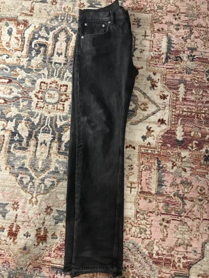 Svarta jeans från 157, straight fit - Svarta jeans från 157 med klassisk femficksdesign och raka ben. Jeansen har en mörk tvätt och rå kant nedtill för en cool, avslappnad vibe. Passar dig som gillar enkel stil med edge. Materialet är slitstarkt jeans och midjan är normal.