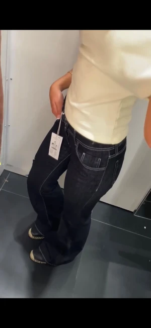  Lågmidjade jeans - Snygga mörkblå bootcut jeans från Gina Tricot med vita kontrastsömmar och låg midja. Jeansen har klassisk femficksdesign och stängs med knapp och dragkedja. Perfekta för dig som gillar en retroinspirerad look med markerade detaljer. De är i storlek 42 men skulle säga att de passar L, även M om du vill ha en baggy look! Fint skick