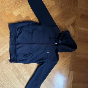 Mörkblå hoodie från Polo Ralph Lauren - Snygg mörkblå hoodie från Polo Ralph Lauren med dragkedja framtill och klassisk logga broderad på bröstet. Tröjan har huva med snörning och två stora fickor framtill. True to size. Priset är inte fast.