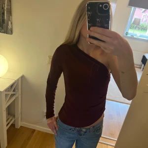 Topp med en ärm - Snygg vinröd tröja med en ärm, väldigt snygg men kommer inte till användning längre. Har en liten fläck längst ner men tycker inte att det är något man lägger märke till!