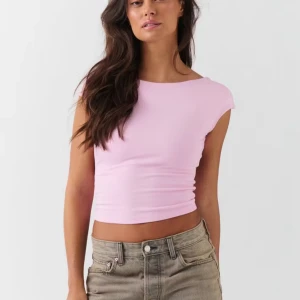 Ljusrosa croppad topp med öppen rygg - Säljer en ljusrosa croppad topp med öppen rygg och korta ärmar. Toppen har en clean och enkel design med mjukt stretchigt material som sitter tight mot kroppen. Nypris är 299