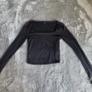 Svart långärmad topp från KappAhl - En svart, långärmad topp med fyrkantig urringning framtill. Super fint material och tjockare tyg framme (dubbeltyg).